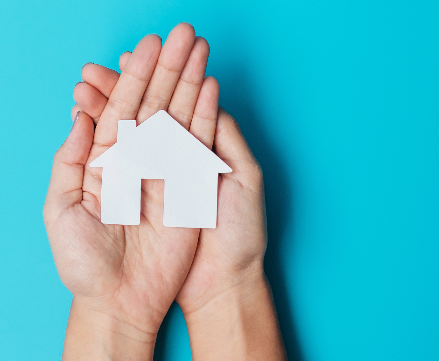 hand holding paper Home cutout on blue background. Real estate,